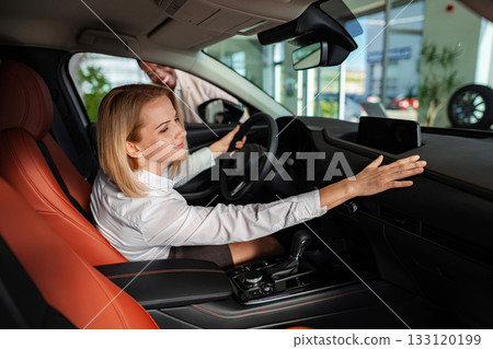 Woman buying new car at dealership showroom 133120199