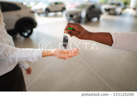 Car salesperson handing over keys to woman at dealership Car salesperson handing over keys to woman at dealership 133120200