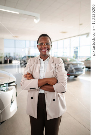 Confident saleswoman working in car dealership showroom Confident saleswoman working in car dealership showroom 133120206