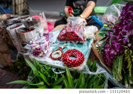 Local street market stall with vendor assembling and selling ceremonial flower wreaths for customers Local street market stall with vendor assembling and selling ceremonial flower wreaths for customers 133120483