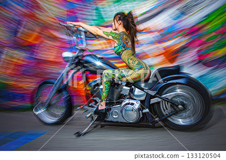 Vibrant motion body painted woman on a custom motorcycle. A woman with intricate body paint poses on a custom motorcycle. Swirl bokeh. Vibrant motion body painted woman on a custom motorcycle. A woman with intricate body paint poses on a custom motorcycle. Swirl bokeh. 133120504