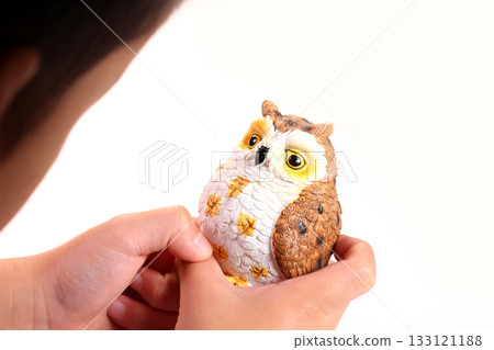 Toddler's hand holding an owl figurine 133121188