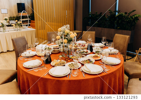 Elegant banquet table with floral centerpiece, candles and appetizers in restaurant 133121293