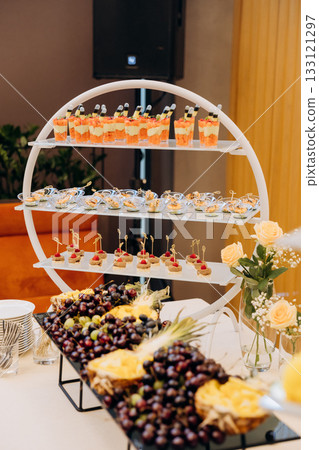 Elegant catering stand with desserts, canapes, and fresh fruit at a formal event Elegant catering stand with desserts, canapes, and fresh fruit at a formal event 133121297