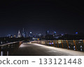 A nighttime view of Warsaw skyline captured from a modern footbridge, with shining skyscrapers and the Palace of Culture glowing in the distance. 133121448