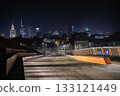 A nighttime view of Warsaw skyline captured from a modern footbridge, with shining skyscrapers and the Palace of Culture glowing in the distance. 133121449