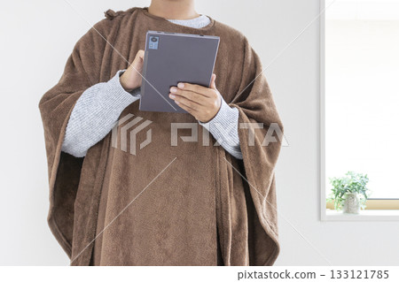 A man in his 30s using a tablet while wearing a wearable blanket (Japanese, no face) 133121785