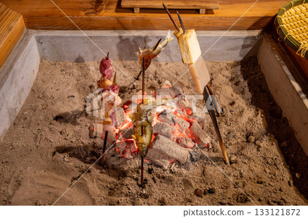 Grilling skewers over charcoal around the hearth Grilling skewers over charcoal around the hearth 133121872