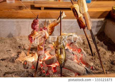 Grilling skewers over charcoal around the hearth Grilling skewers over charcoal around the hearth 133121873