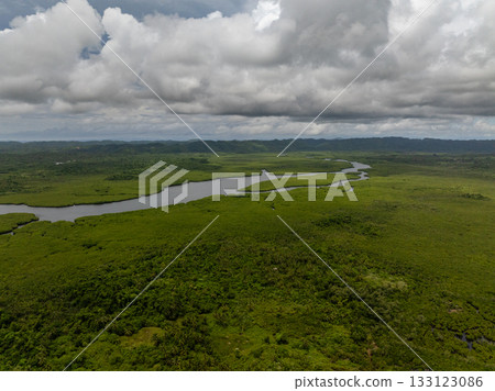 Wide river winds between mangrove forest with distant mountains and blue sky. Siargao, Philippines. Wide river winds between mangrove forest with distant mountains and blue sky. Siargao, Philippines. 133123086