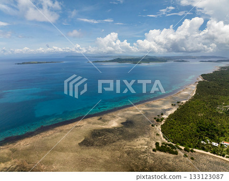 Aerial view of coastline with coral reef and clear blue water under blue sky. Siargao, Philippines. Aerial view of coastline with coral reef and clear blue water under blue sky. Siargao, Philippines. 133123087