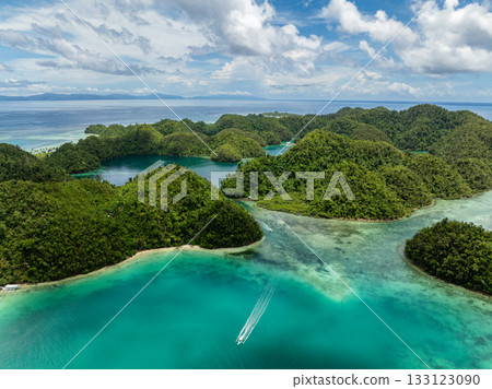 Turquoise tropical bay with boats moving between green forested islands. Siargao, Philippines. Sugba Blue Lagoon. 133123090