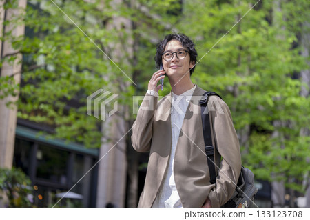 一名三十多歲的男子在城市裡用智慧型手機通話 133123708
