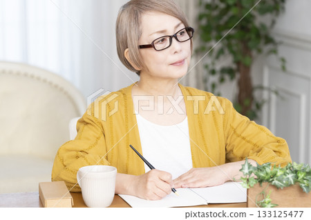 Senior woman writing an end-of-life note in the living room Senior woman writing an end-of-life note in the living room 133125477