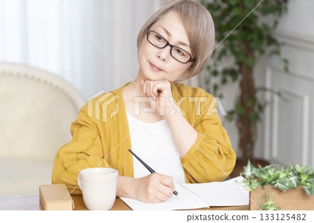 Senior woman writing an end-of-life note in the living room 133125482