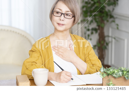 Senior woman writing an end-of-life note in the living room Senior woman writing an end-of-life note in the living room 133125485