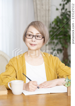 Senior woman writing an end-of-life note in the living room Senior woman writing an end-of-life note in the living room 133125512