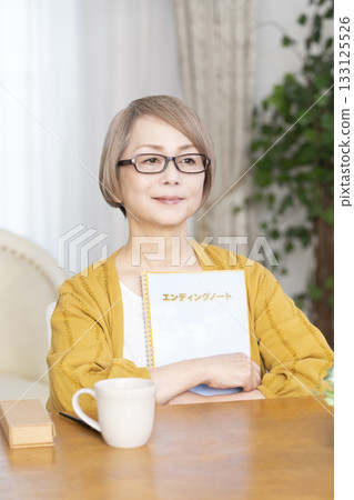 Senior woman writing an end-of-life note in the living room Senior woman writing an end-of-life note in the living room 133125526