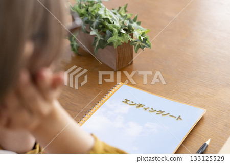 Senior woman writing an end-of-life note in the living room 133125529