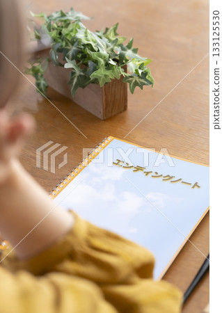 Senior woman writing an end-of-life note in the living room 133125530