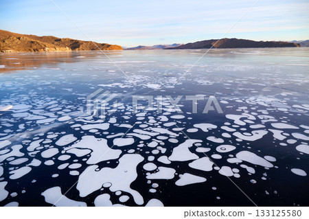 Frozen Lake Baikal on a winter day. Transparent, smooth ice with large methane bubbles Frozen Lake Baikal on a winter day. Transparent, smooth ice with large methane bubbles 133125580