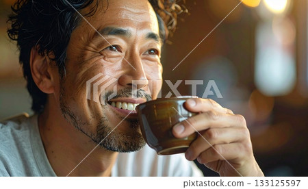 A man slowly drinking tea from a teacup 133125597