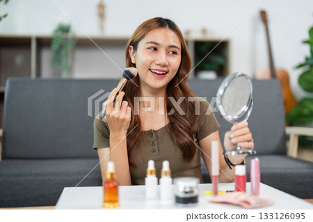 Makeup Application. Young woman smiling while applying blush in front of mirror. 133126095