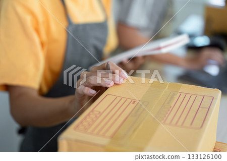 Small Business Operations. Employee preparing packages for shipment in a retail workspace. Small Business Operations. Employee preparing packages for shipment in a retail workspace. 133126100