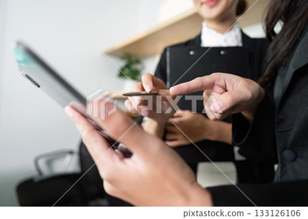 Collaboration and Teamwork. Businesswomen discussing project details with tablet in modern office. Collaboration and Teamwork. Businesswomen discussing project details with tablet in modern office. 133126106