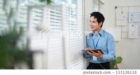 Smiling Young Professional Using Tablet by Window Smiling Young Professional Using Tablet by Window 133126118