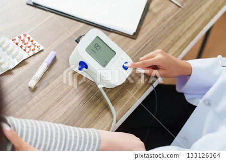 Blood Pressure Monitoring. Doctor using a device to check patient's blood pressure. 133126164