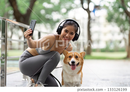 Wellness and Connection. Young woman taking a selfie with her corgi dog in a park. Wellness and Connection. Young woman taking a selfie with her corgi dog in a park. 133126199