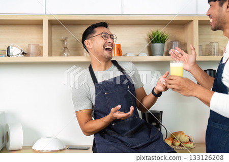 Couple Sharing a Drink. Men laughing and enjoying beverages in a modern kitchen. 133126208