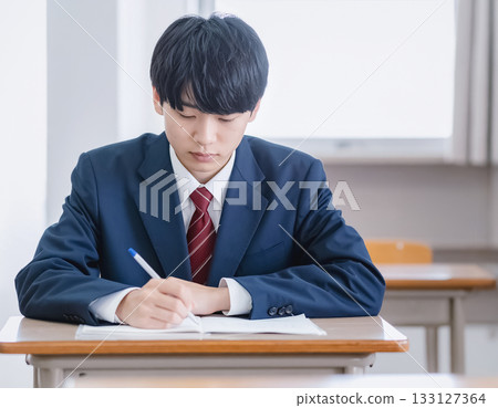 一名男學生在安靜的教室裡學習。 一名男學生在安靜的教室裡學習。 133127364
