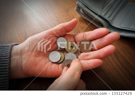 一位老婦人的手在數著掌心的硬幣,桌上放著一個錢包。 一位老婦人的手在數著掌心的硬幣,桌上放著一個錢包。 133127429