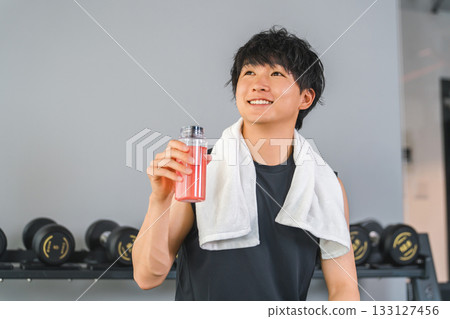 A young Asian man drinking EAA, protein during breaks and intervals at a fitness gym (hydration) A young Asian man drinking EAA, protein during breaks and intervals at a fitness gym (hydration) 133127456