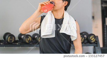A young Asian man drinking EAA, protein during breaks and intervals at a fitness gym (hydration) A young Asian man drinking EAA, protein during breaks and intervals at a fitness gym (hydration) 133127457