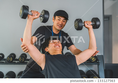 Young Asian man receiving personal training at a sports gym 133127563