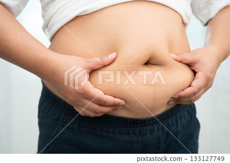 Asian woman use hand to squeeze fat belly big size overweight and obesity. 133127749