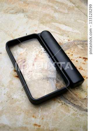 Large magnifying glass on a marble table 133128299