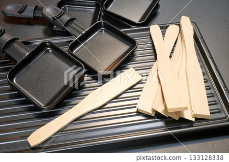 Raclette trays and wooden pallets on table Raclette trays and wooden pallets on table 133128338