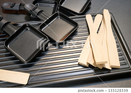 Raclette trays and wooden pallets on table Raclette trays and wooden pallets on table 133128339