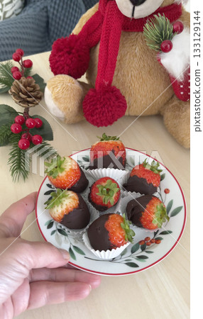 Chocolate-covered strawberries on ceramic saucer. Christmas dessert. Holidays and decorations, food. 133129144