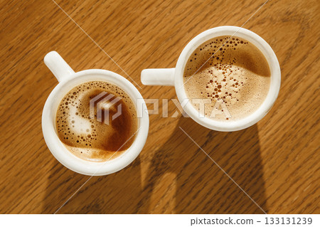 Two White Cups of Cappuccino With Rich Foam on Wooden Table, Top View  133131239