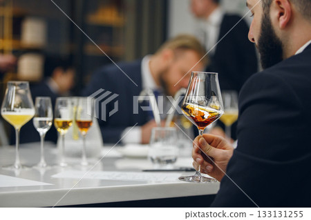 Sommelier looking at color of drink during alcohol beverages training. Training of restaurant staff, studying alcohol list. Sommelier looking at color of drink during alcohol beverages training. Training of restaurant staff, studying alcohol list. 133131255
