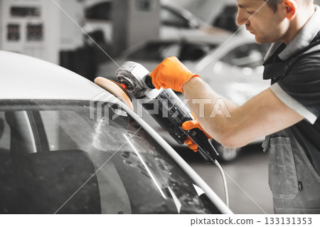 Worker polished white car with orbital polisher in auto repair shop, close-up. Vehicle detailing. Worker polished white car with orbital polisher in auto repair shop, close-up. Vehicle detailing. 133131353