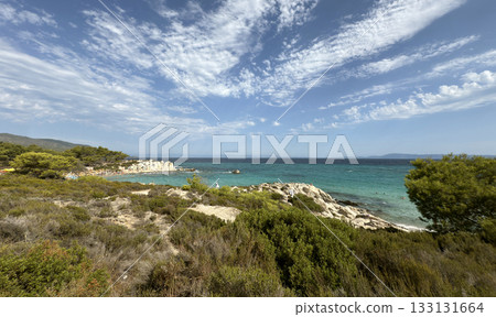 View of Kavourotrypes beach, official nudist beach, Summer sunny day blue sky sea stones, people sunbathing. Sithonia peninsula, Greece View of Kavourotrypes beach, official nudist beach, Summer sunny day blue sky sea stones, people sunbathing. Sithonia peninsula, Greece 133131664