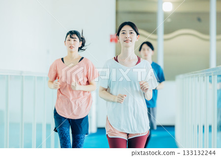 Men and women running on an indoor track 133132244