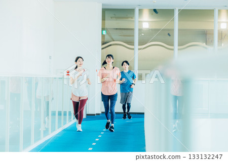 Men and women running on an indoor track 133132247