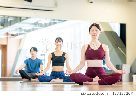 Young men and women practicing yoga in a yoga studio 133133267
